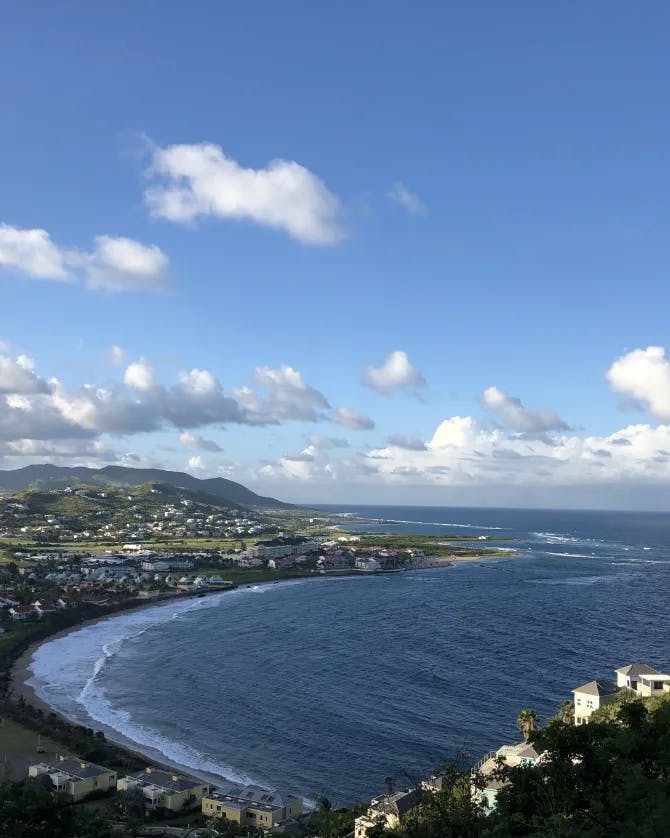 An aerial view of St Kitts And Nevis Frigate Bay Of The South highlighting blue water and a town built into a coastal mountain range
