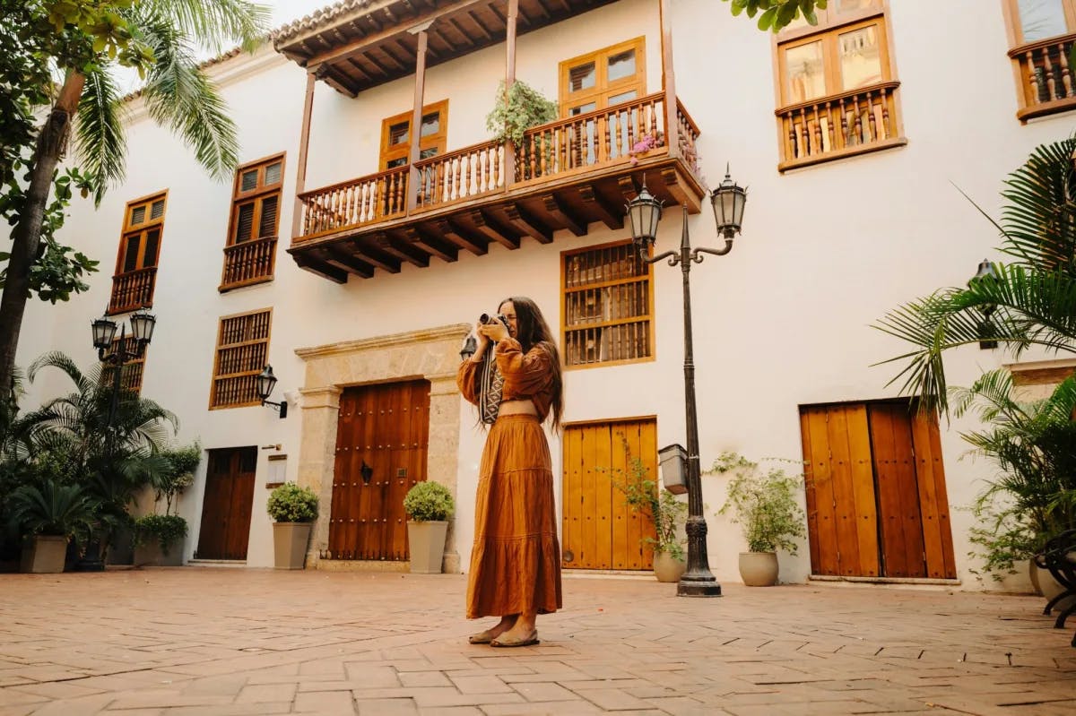 A woman in local attire takes pictures of the architecture in a historic courtyard in Bolivar Columbia