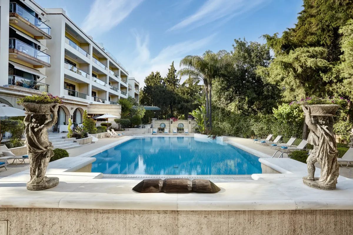 Classical statues and hedge art surrounds an elegant pool courtyard at Rodos Park in Rhodes, Greece
