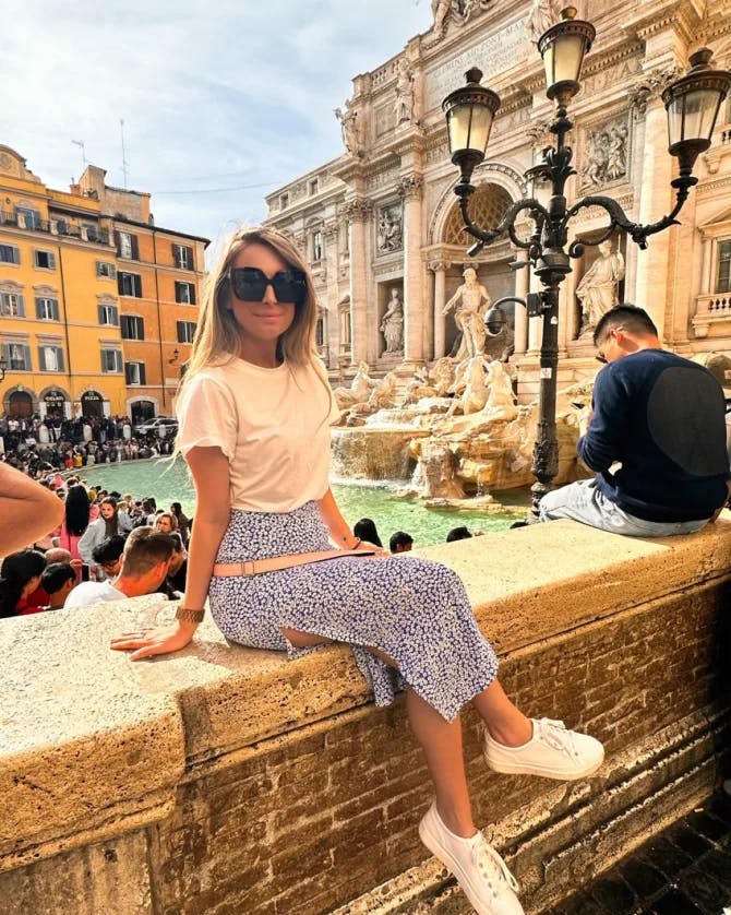 Picture of Lauren sitting with a water fountain behind her in Italy. 