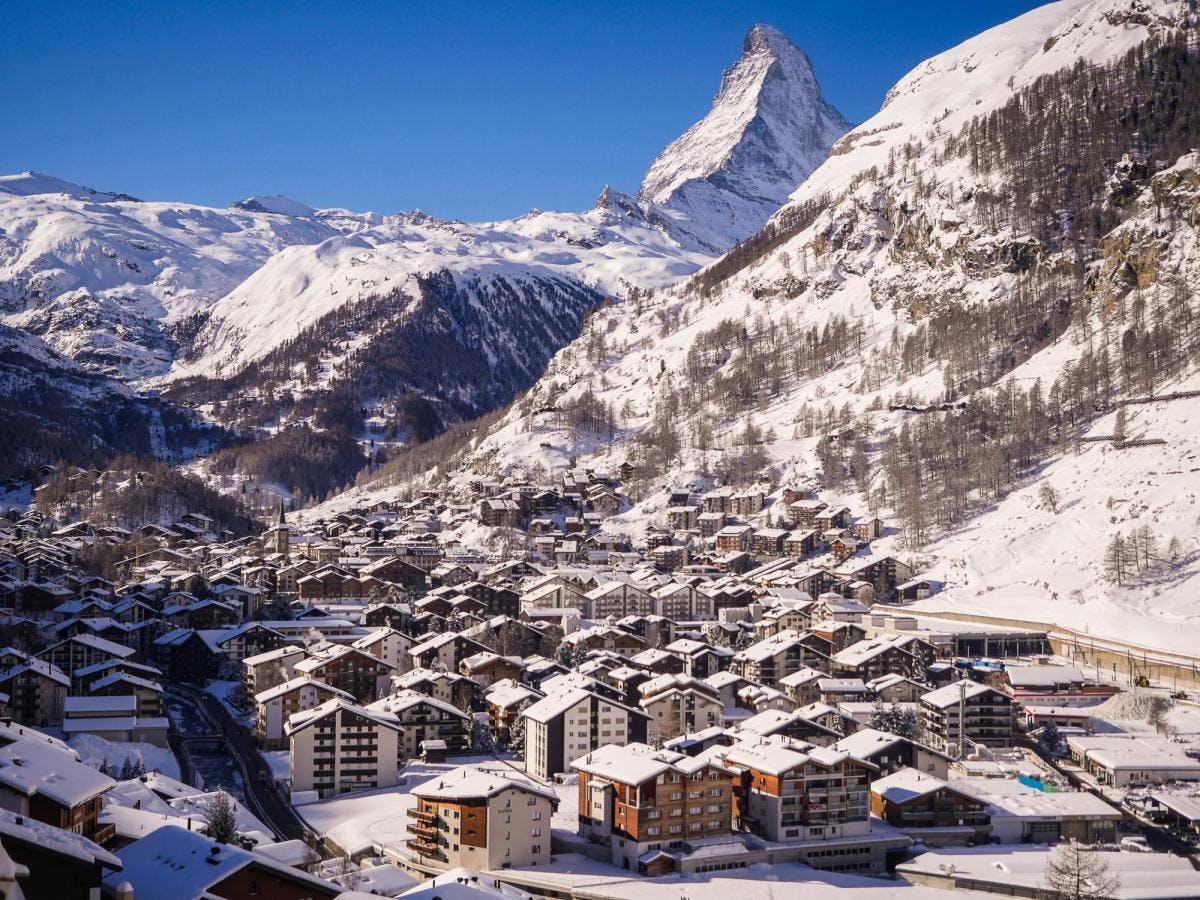 Ski resorts and lodges nestled at the foot of snowy Matterhorn mountain in winter in Zermatt.