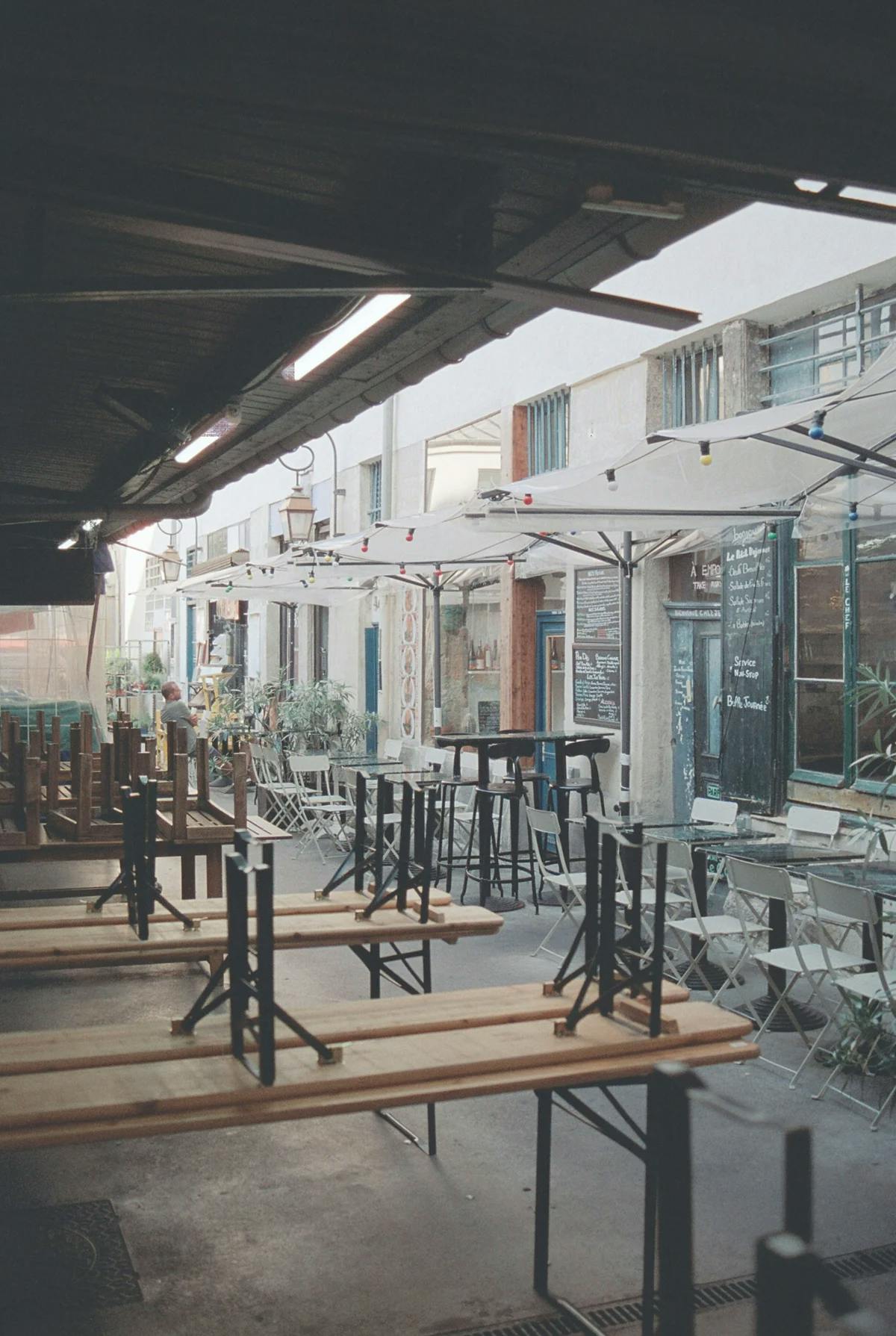 The Marché des Enfants Rouges in the Paris 3rd arrondissement, with outdoor patio tables and umbrellas under an awning.