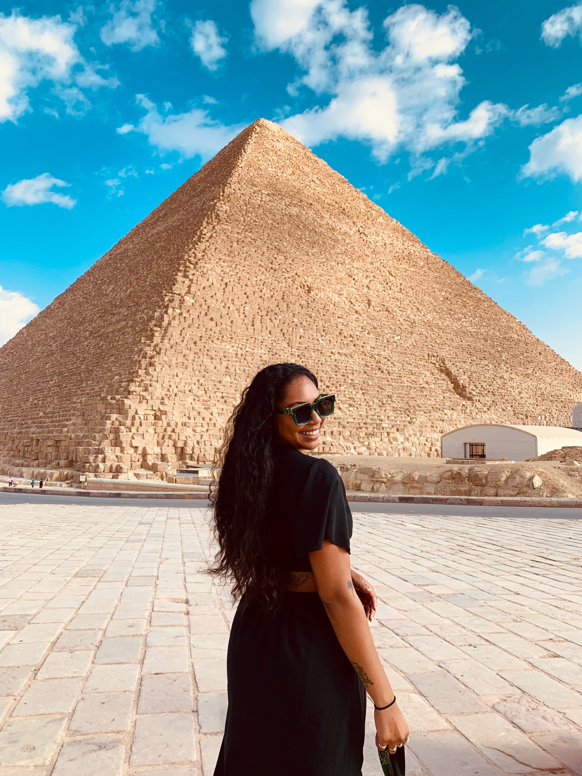 Travel advisor stands in front of pyramid wearing a black dress