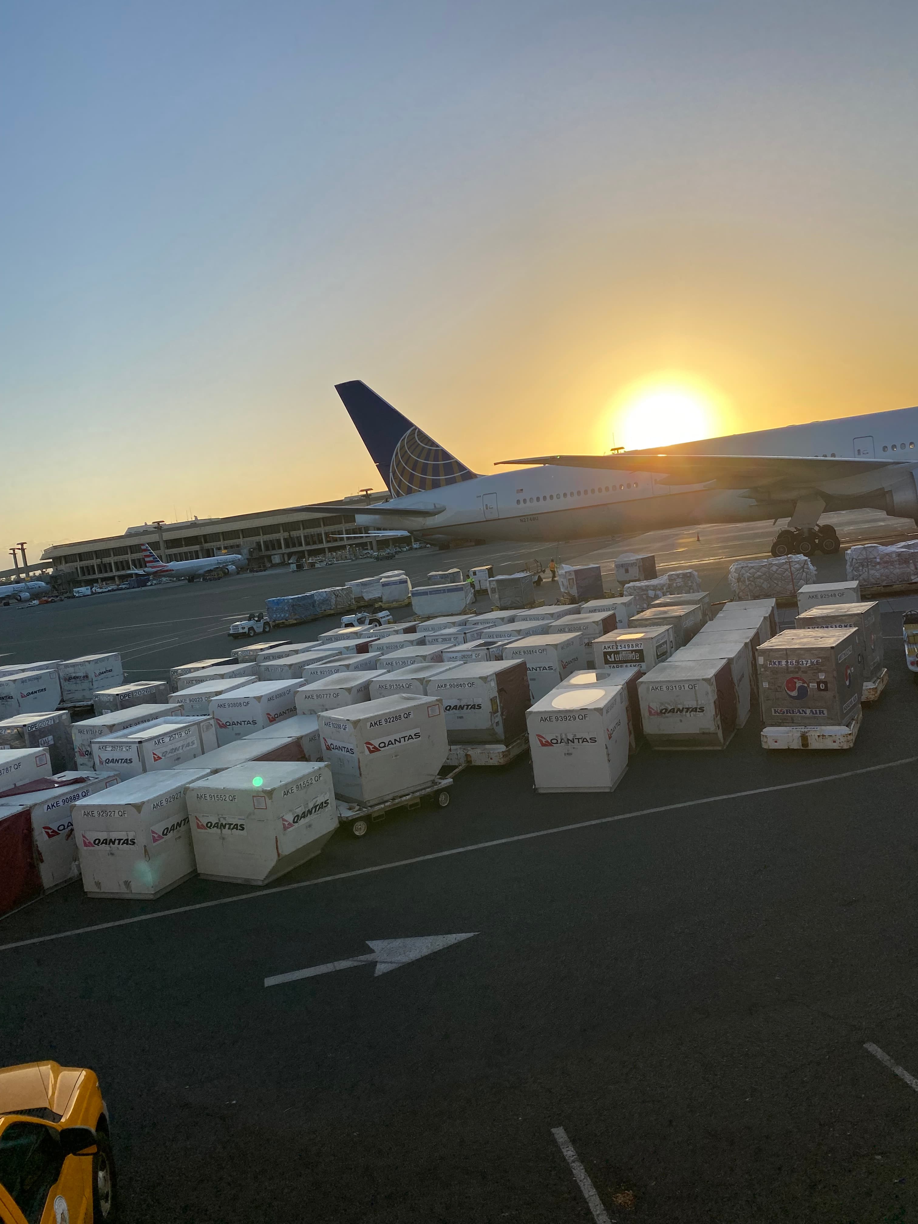 A beautiful view of a sunset at the airport over an airplane and machinery