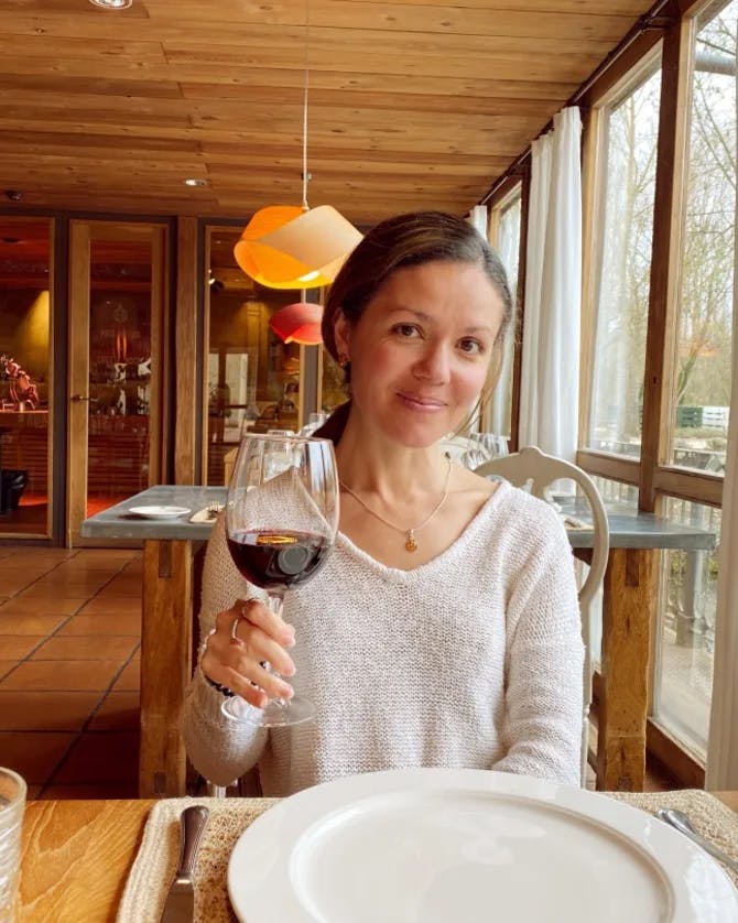 travel advisor Amalia Maloney holds up a glass of red wine in a restaurant