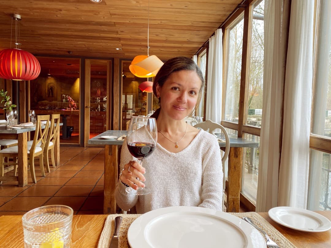 travel advisor Amalia Maloney holds up a glass of red wine in a restaurant