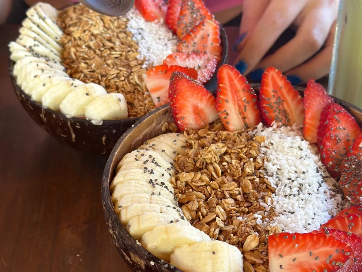 Acai bowls topped with strawberries, bananas, granola and coconut