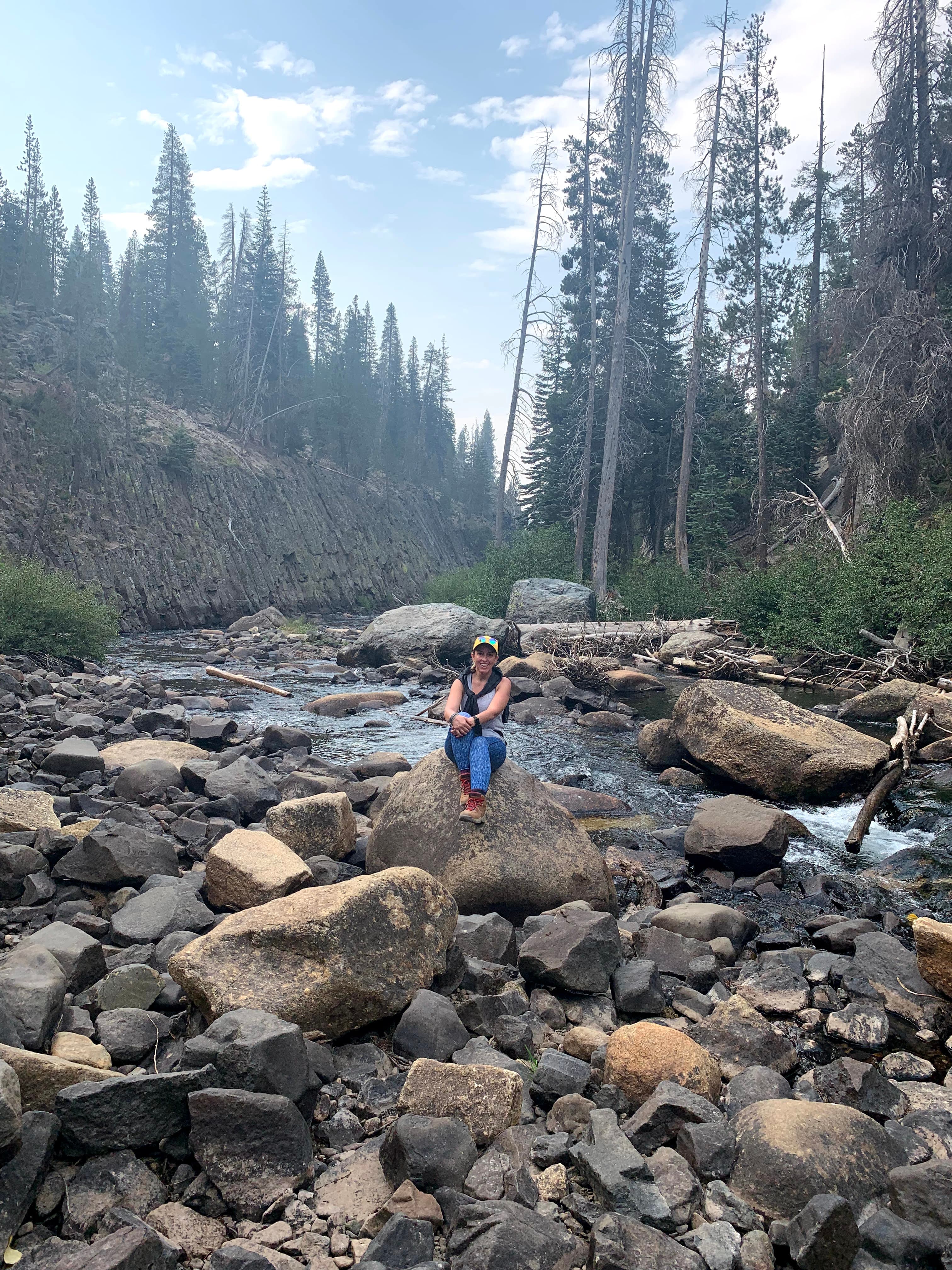 Picture of Ana sitting on stones near water