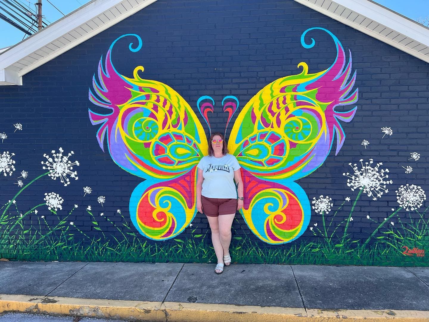 A woman posing in front of butterfly wall art.
