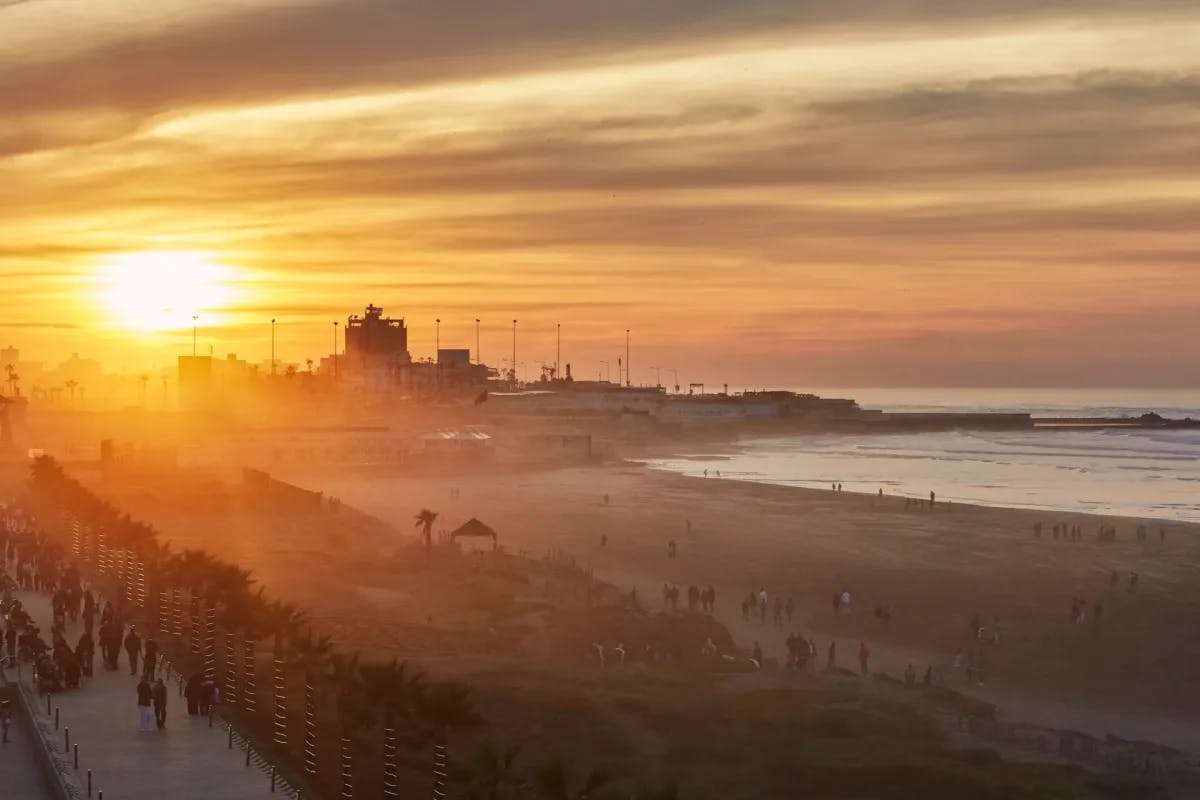 At sunset, from the point of view of Four Seasons Hotel Casablanca's roof: dozens of travelers stroll along the waterfront promenade and beach just outside the hotel