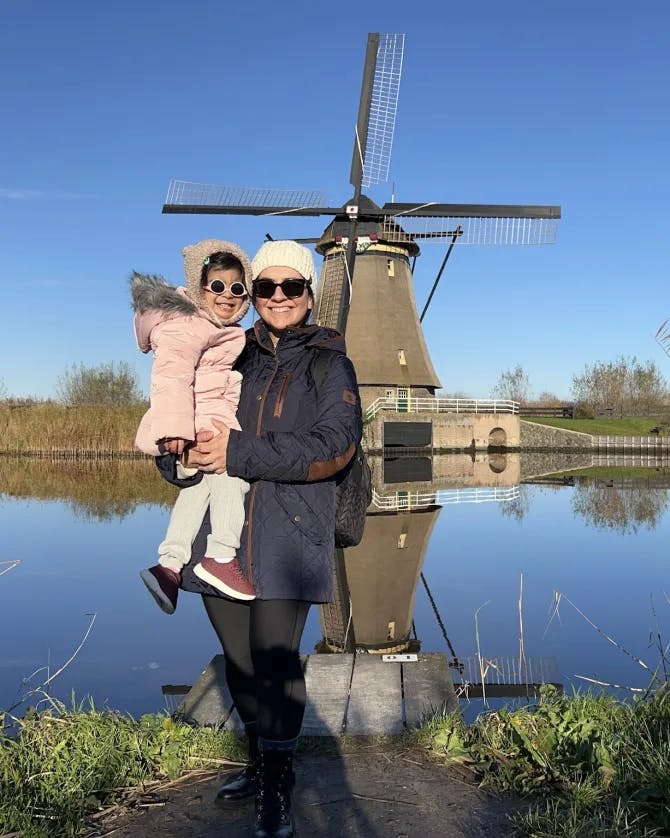 Advisor holding a child while posing in front of a windmill
