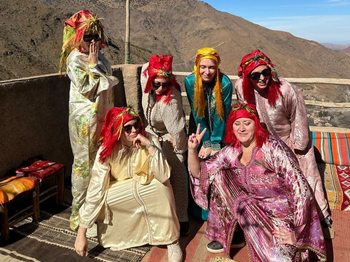 A group of women in traditional clothing posing for a photo with a mountain in the background