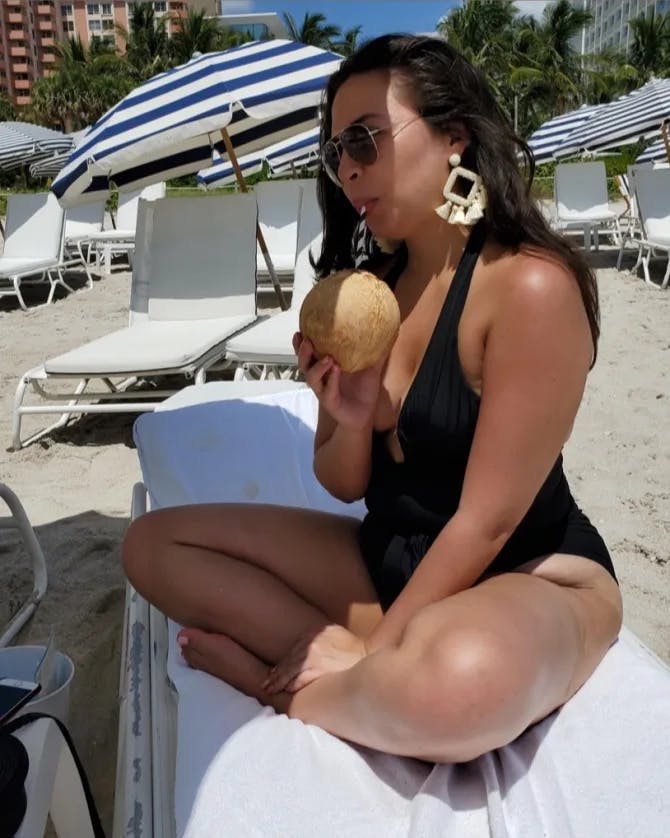 Robyn Srednicki on the beach drinking a coconut