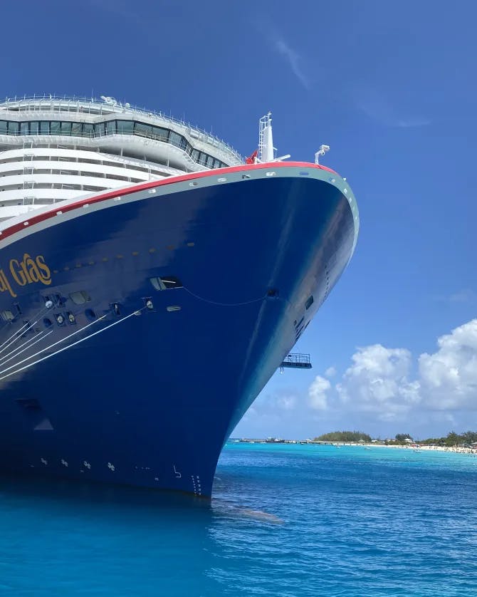 A blue cruise ship docked over bright blue water 