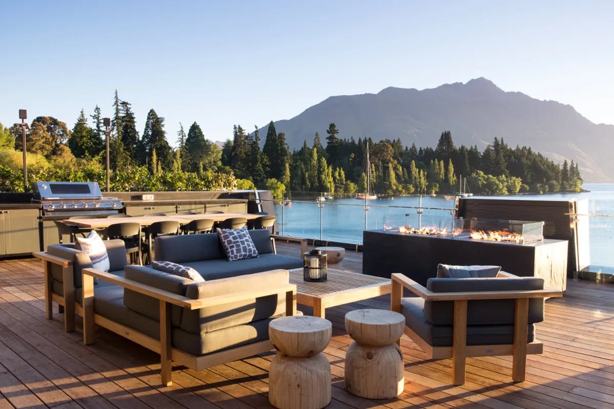 chairs and couches on an outdoor wooden terrace overlooking a lake
