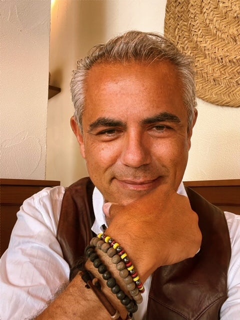 Travel Advisor Joan Carles Gomez Garcia wears a white shirt, brown vest, and brown beaded bracelets
