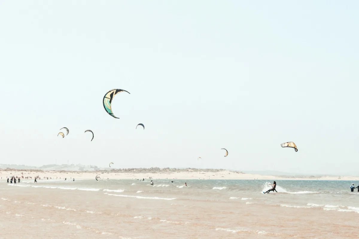 Dozens of kitesurfers ride the waves at Essaouira, Morocco as onlookers stand along the shoreline