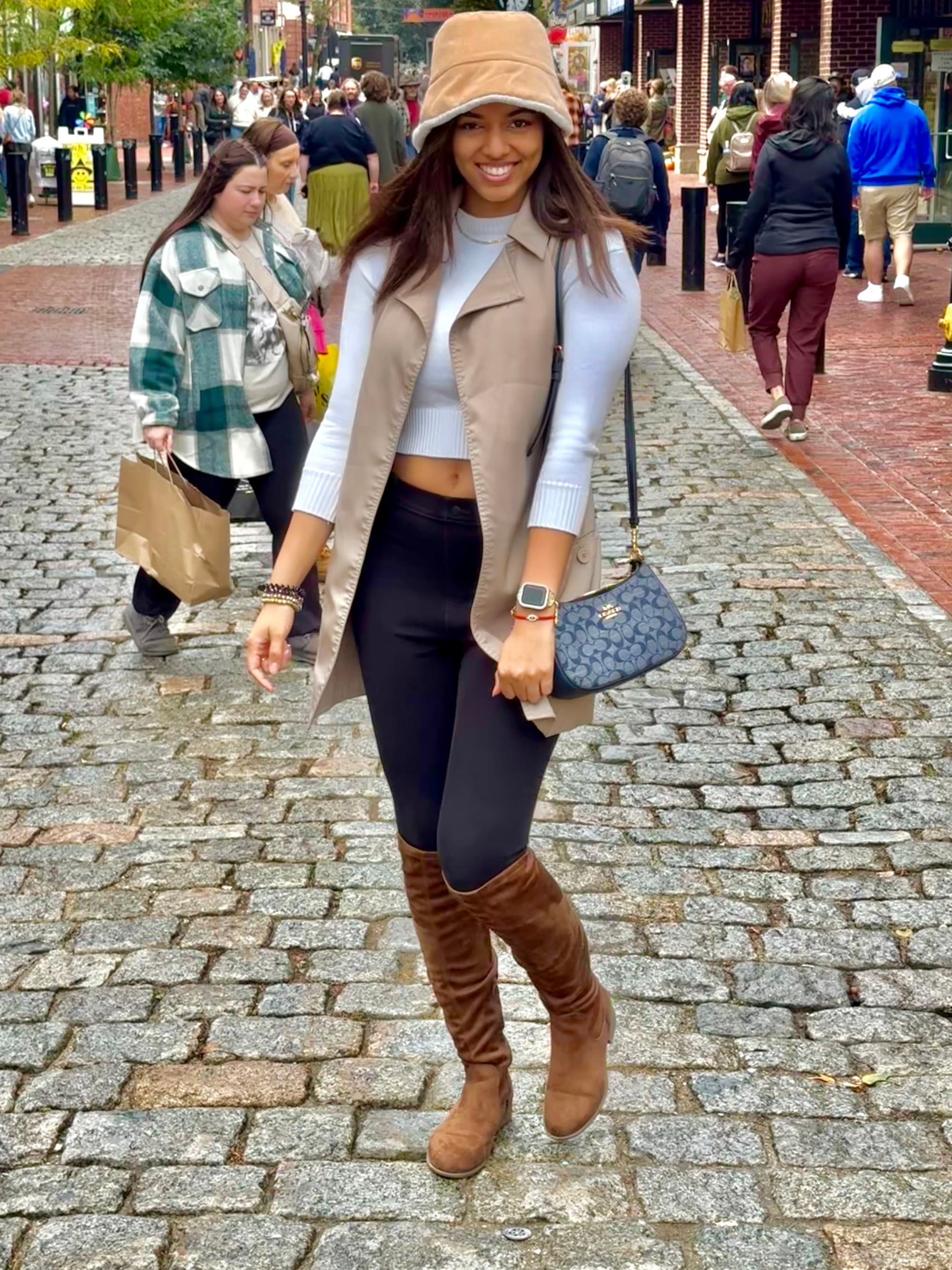 Travel advisor in city wearing long boots and brown hat.