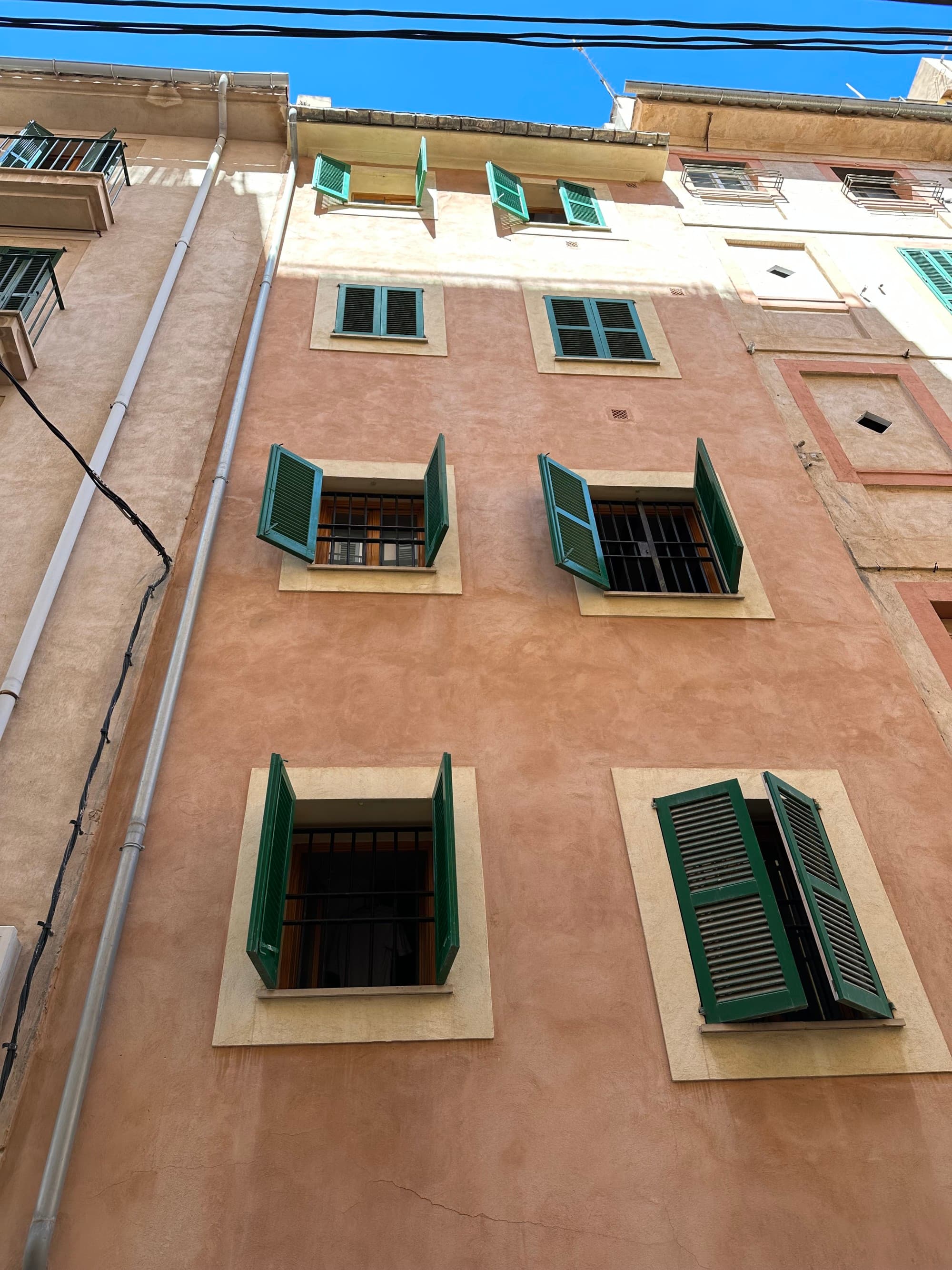 A light brown building with green windows.