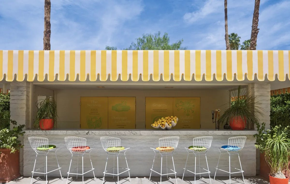 a white outdoor bar with a basket full of lemons and a yellow-and-white striped awning