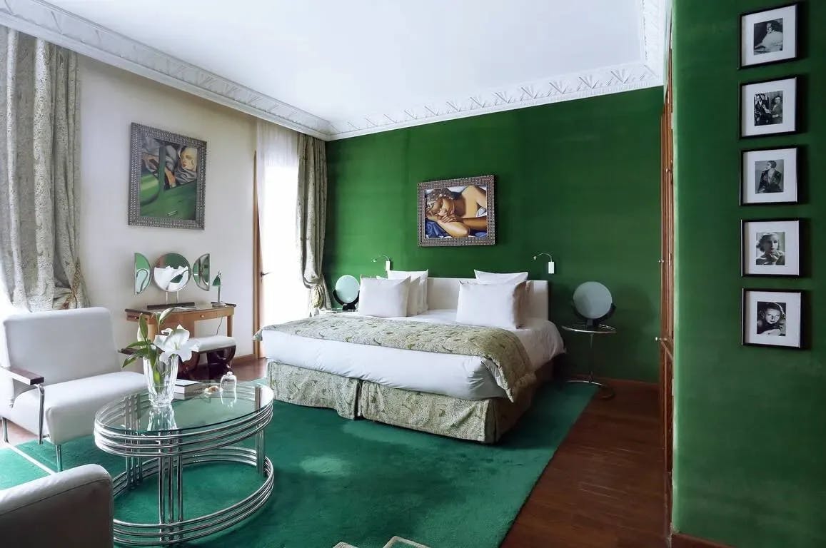A vivid green rug and walls contrast with elegant white furnishings in a room at Hôtel Le Doge - Relais & Châteaux