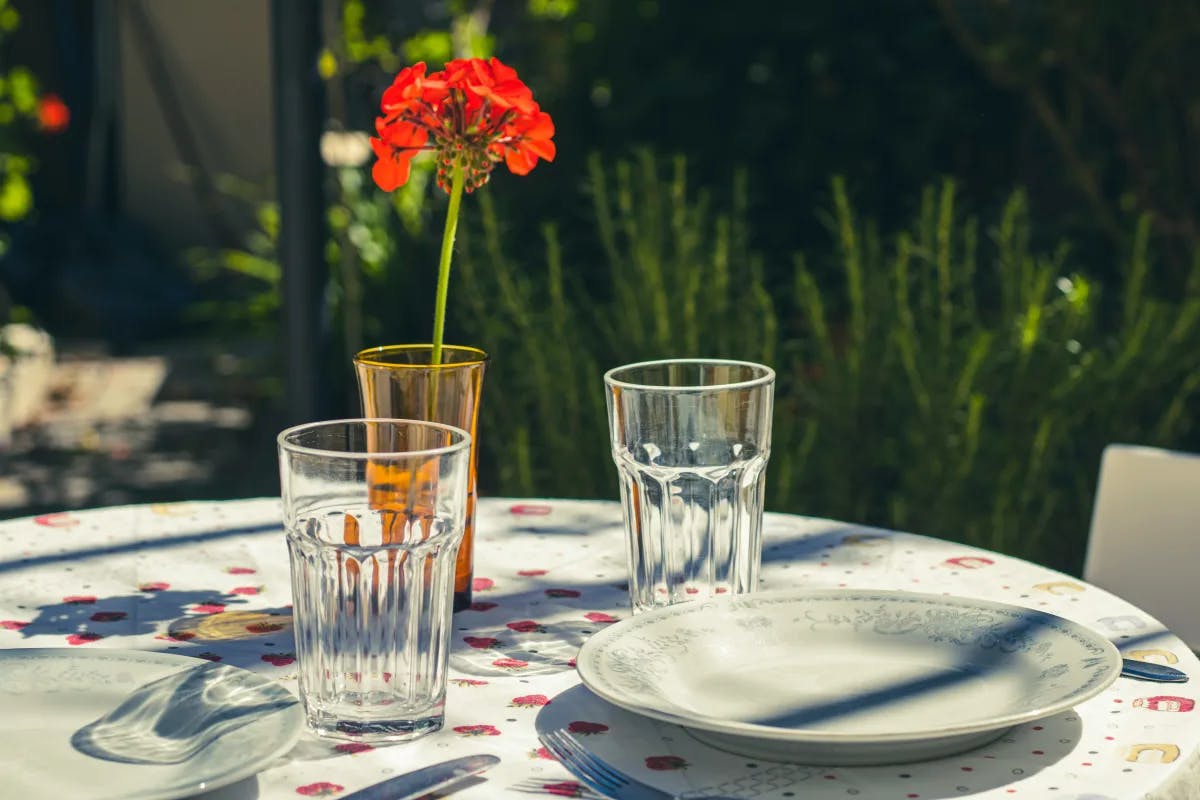 A picture of an outdoor restaurant table with clear glasses and ceramic plates.