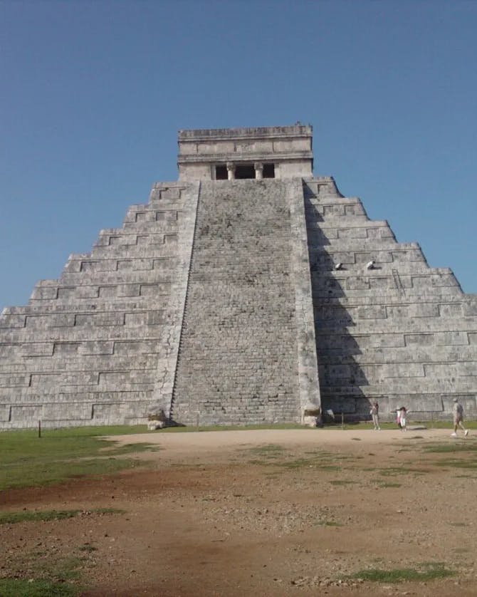 A picture of El Castillo on a sunny day with a dirt path and grass surrounding it