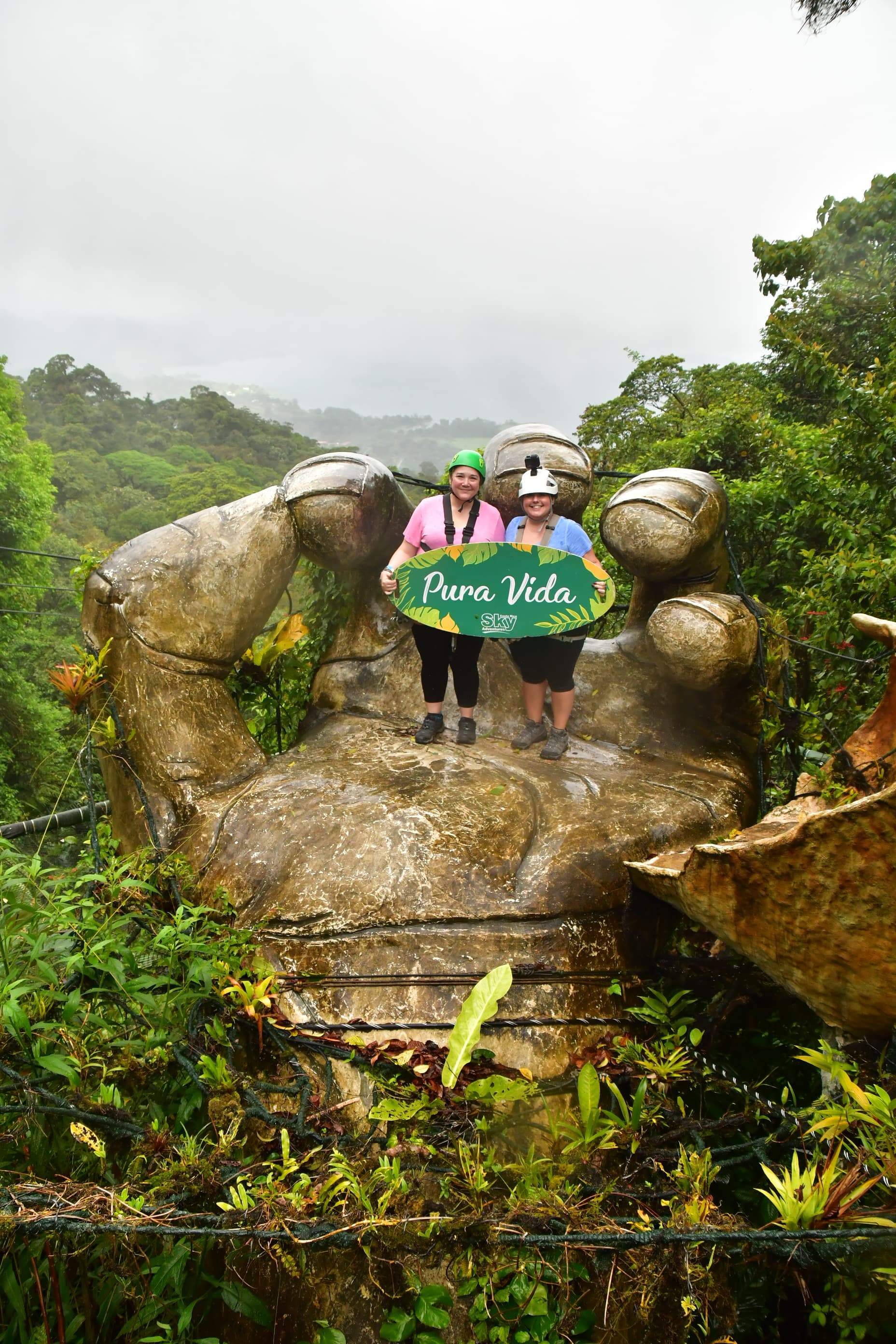 Two women on a landmark shaped as hand.