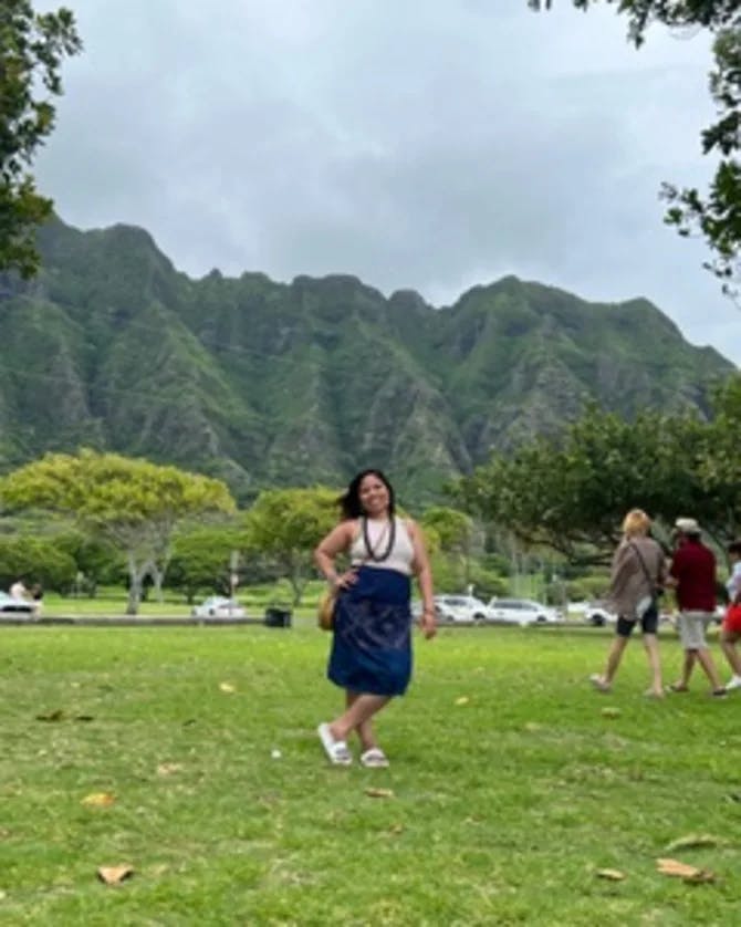 Rogelyn Davis posing in front of a green mountain in Hawaii.