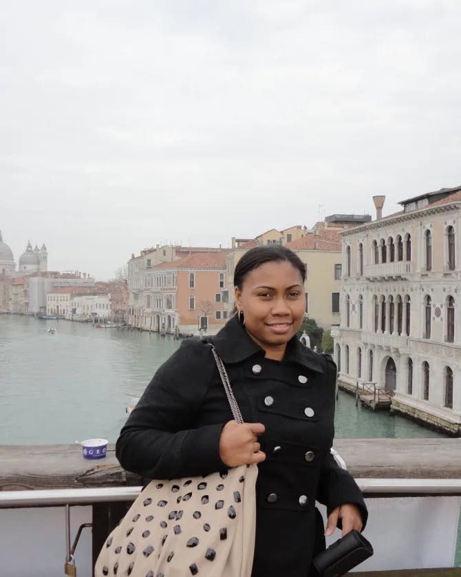 Picture of Lola at Ponte dell'Accademia bridge wearing a black coat and holding a polka dot printed bag