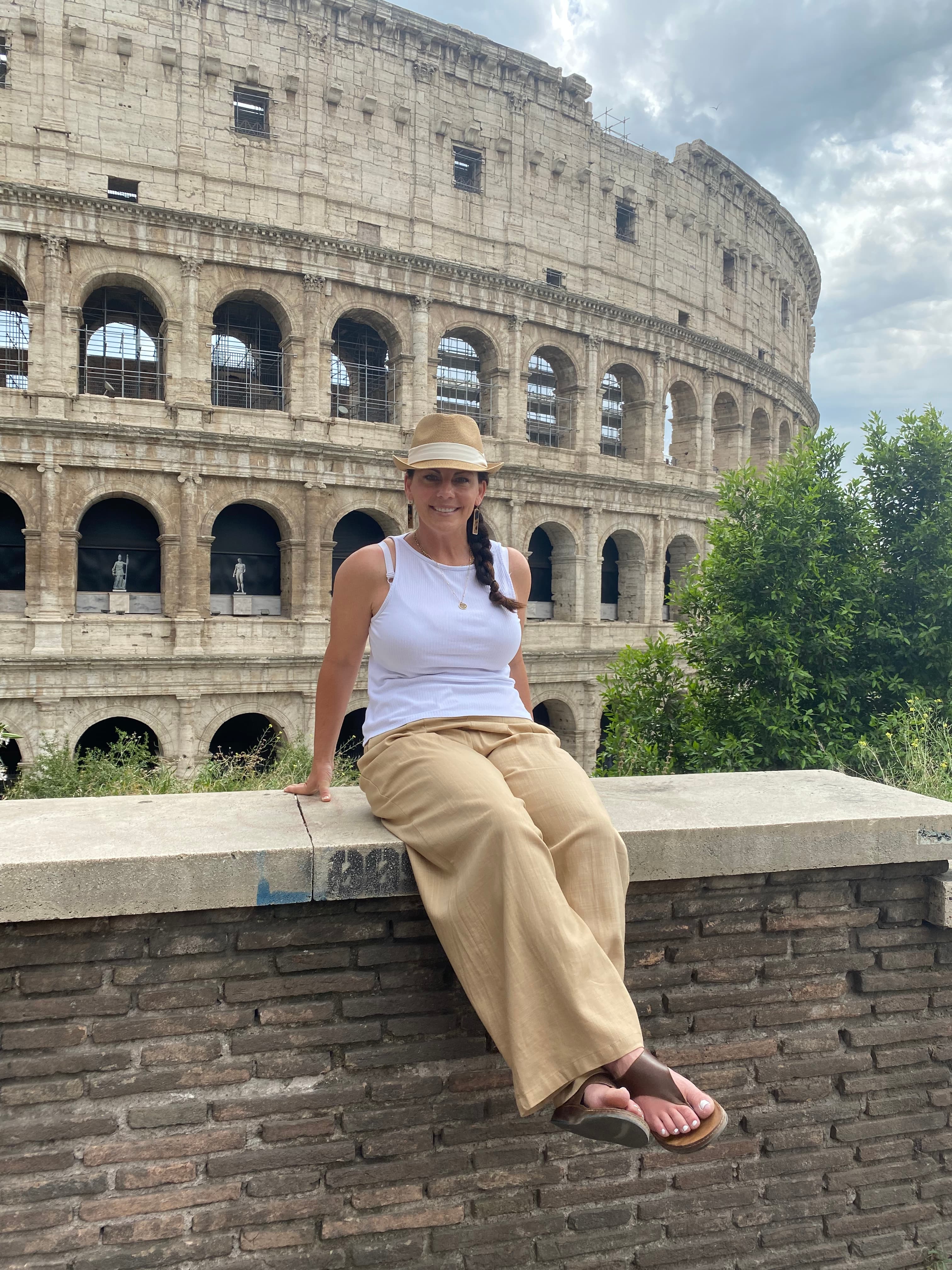 Woman posing sitting on a wall in front of the Colosseum