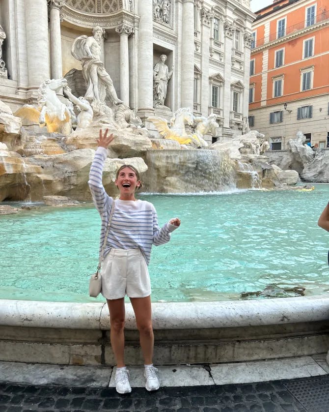 Picture of Shelby throwing a coin into the Trevi fountain while wearing a striped top and white shorts