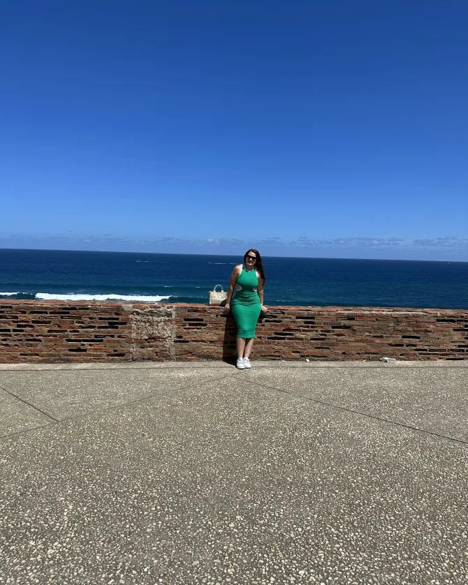 Picture of Juanita wearing a green dress at San Juan with the ocean in the background