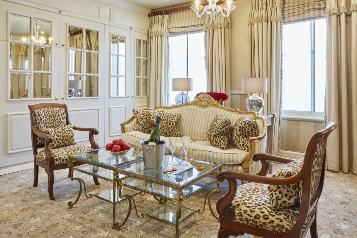 Cheetah-print vintage furniture flanks an elegant glass-top table. Off-white drapes hang along large windows. And elegant decor fills an otherwise posh yet traditional room