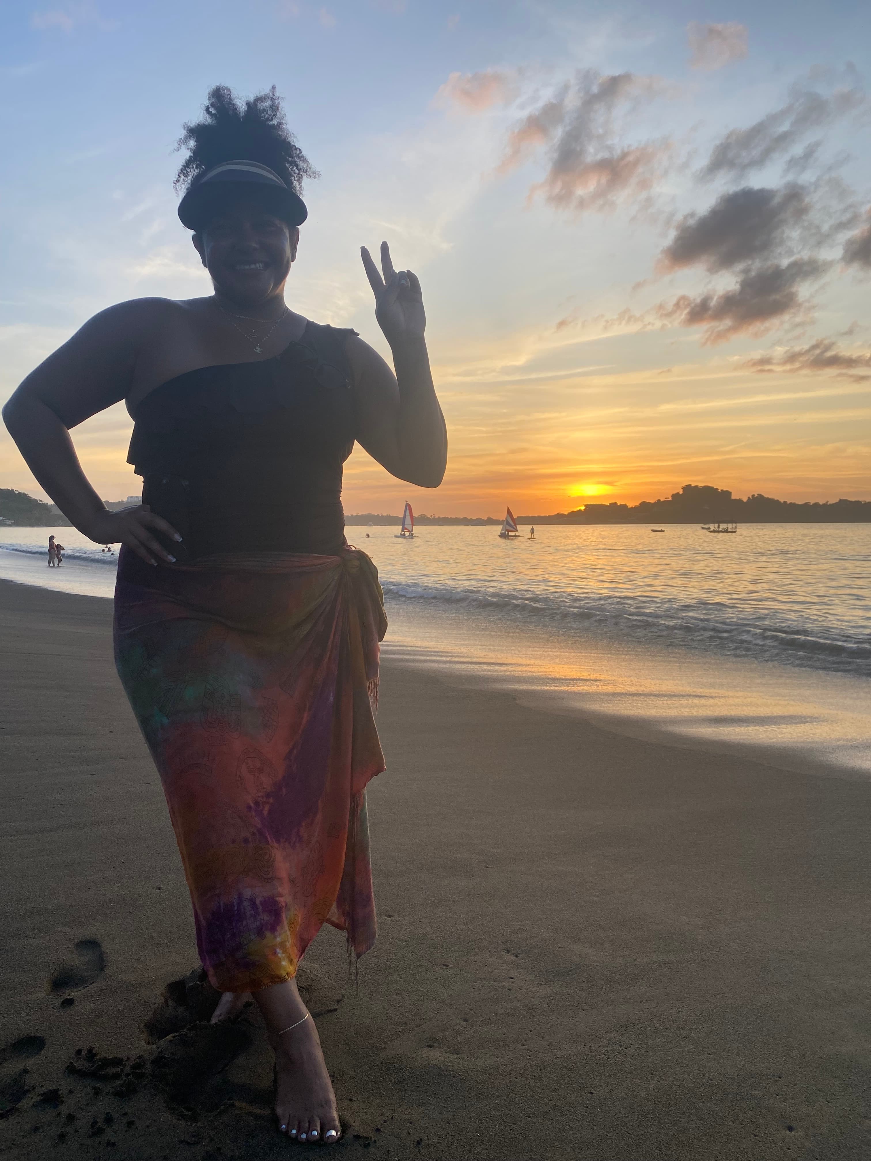 Shannon posing for sunset by the seashore with golden rays along the horizon.