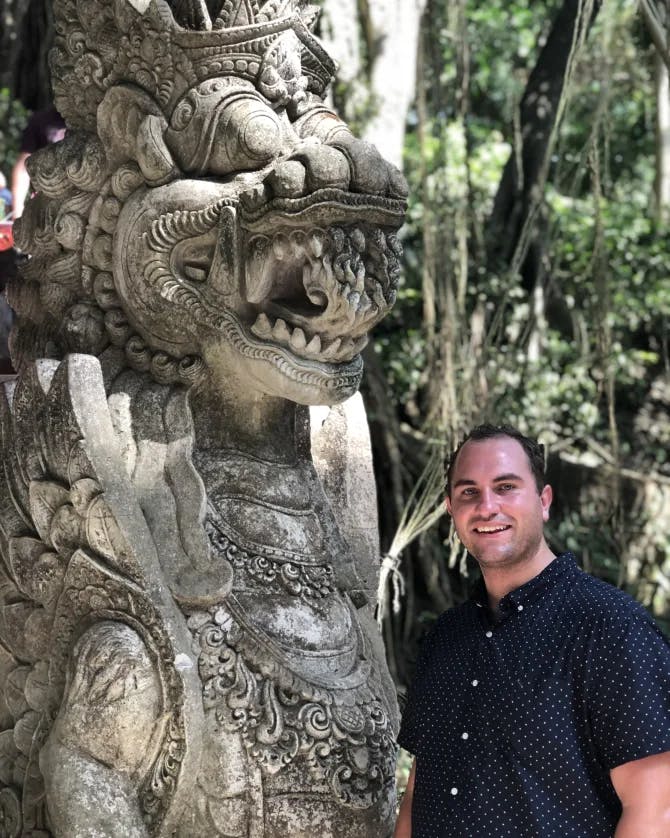  Nicholas posing next to a stone statue in the jungle. 