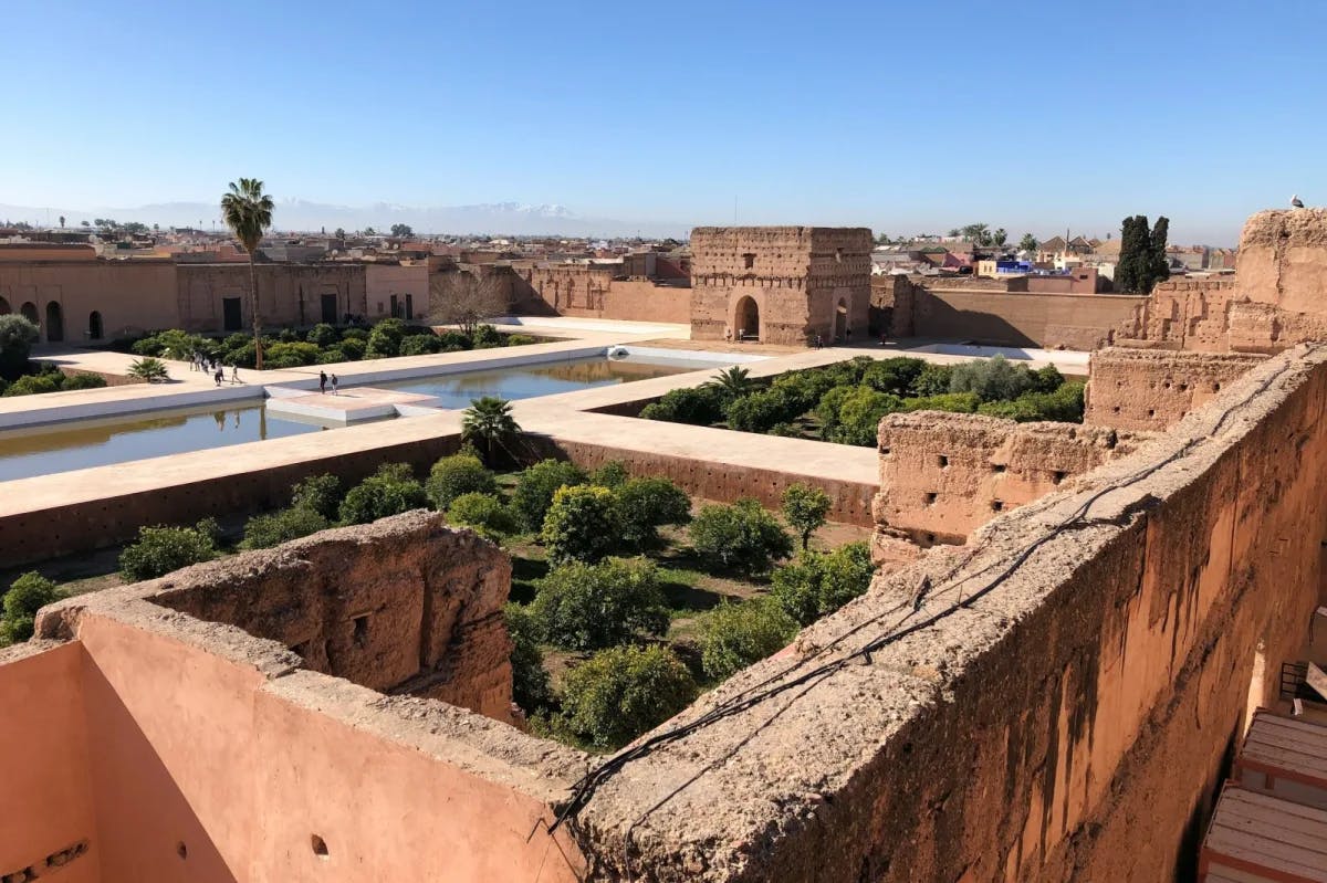 An archeology site in Marrakech with clay walls and a fort surrounding pools and gardens