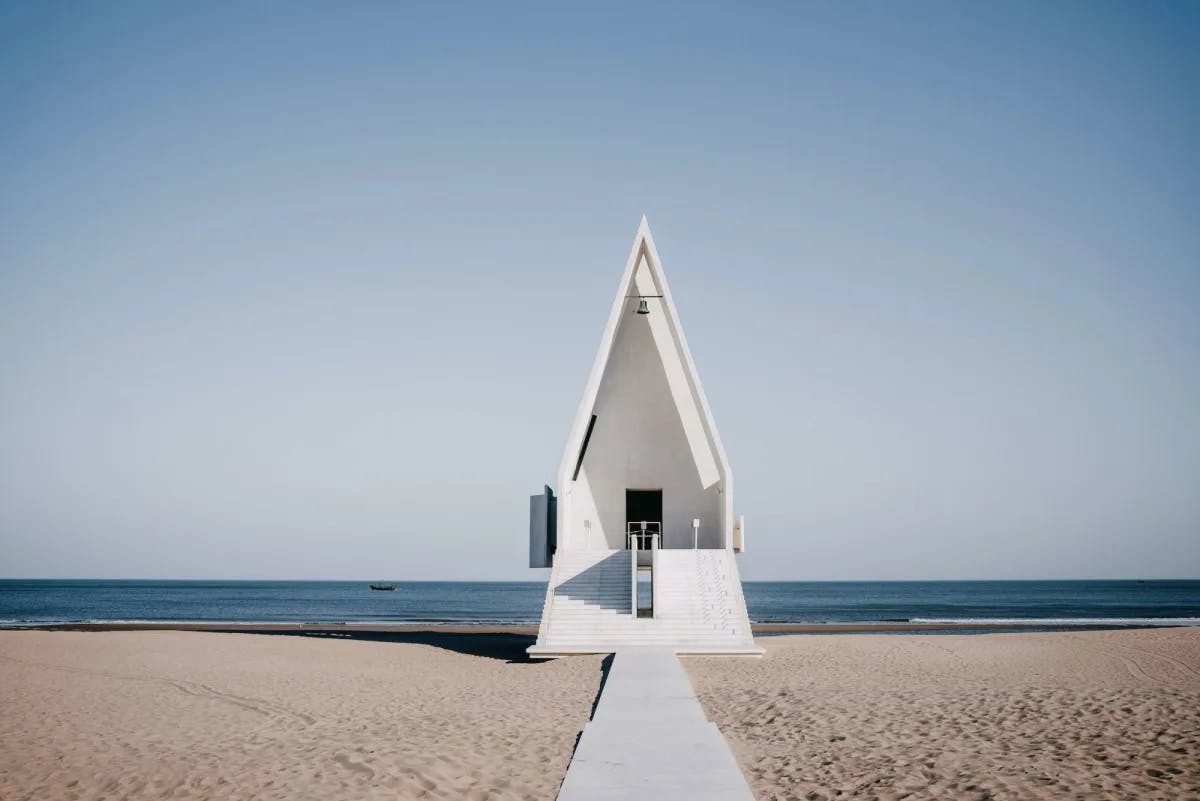 The angular structure of a thin, white church set on a pristine, empty beach in Aranya, China