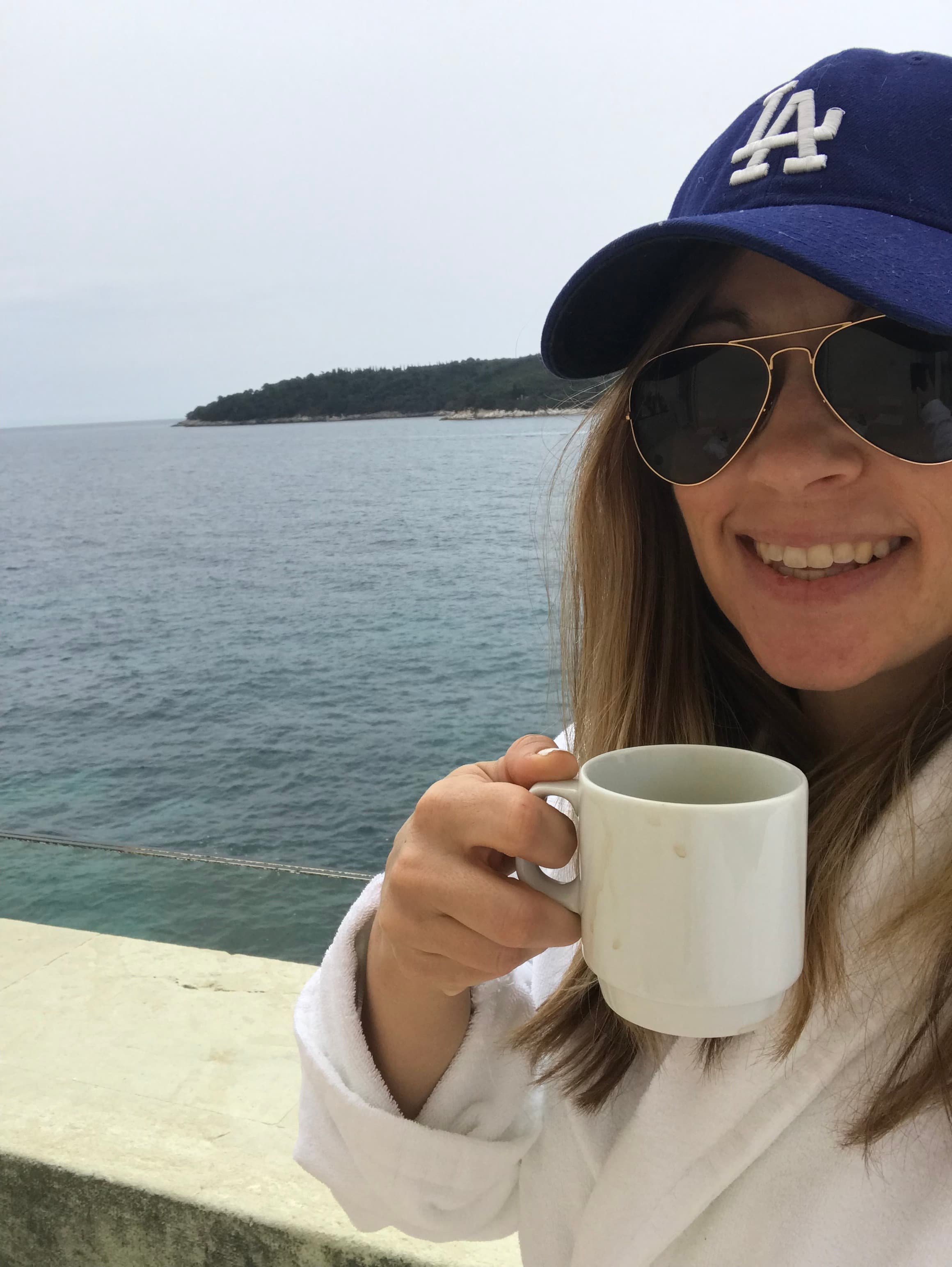 Travel advisor posing with a cup beside the sea
