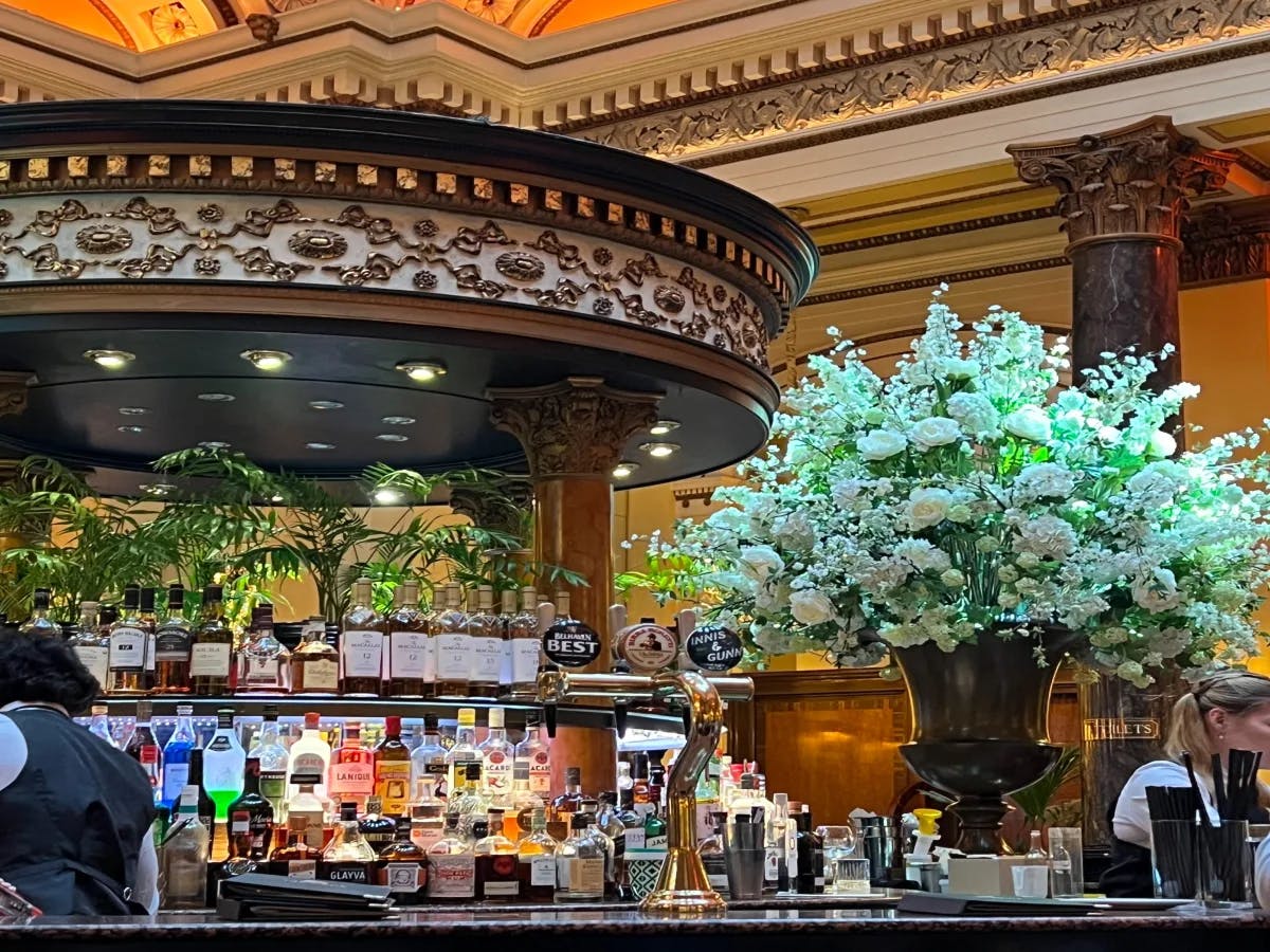 A picture of a bar at a restaurant with a vase filled with white flowers placed on the counter.