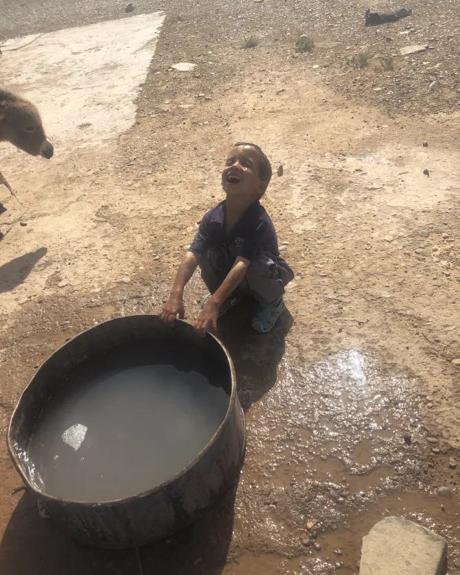A boy sitting with a water trough