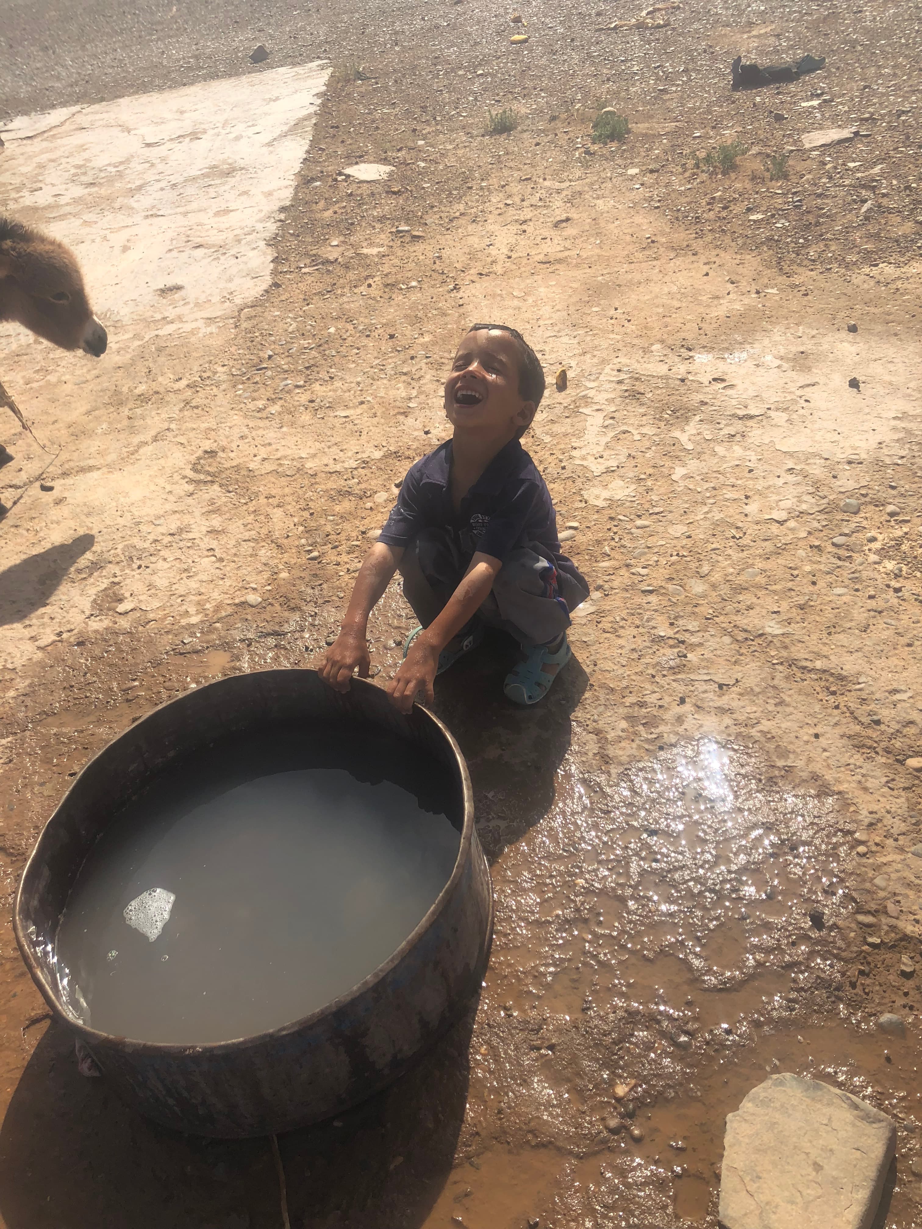A boy sitting with a water trough