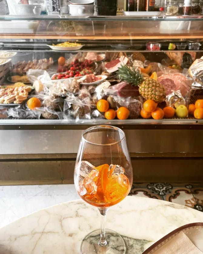 An Aperol Spritz placed on a table in front of an arrangement of food