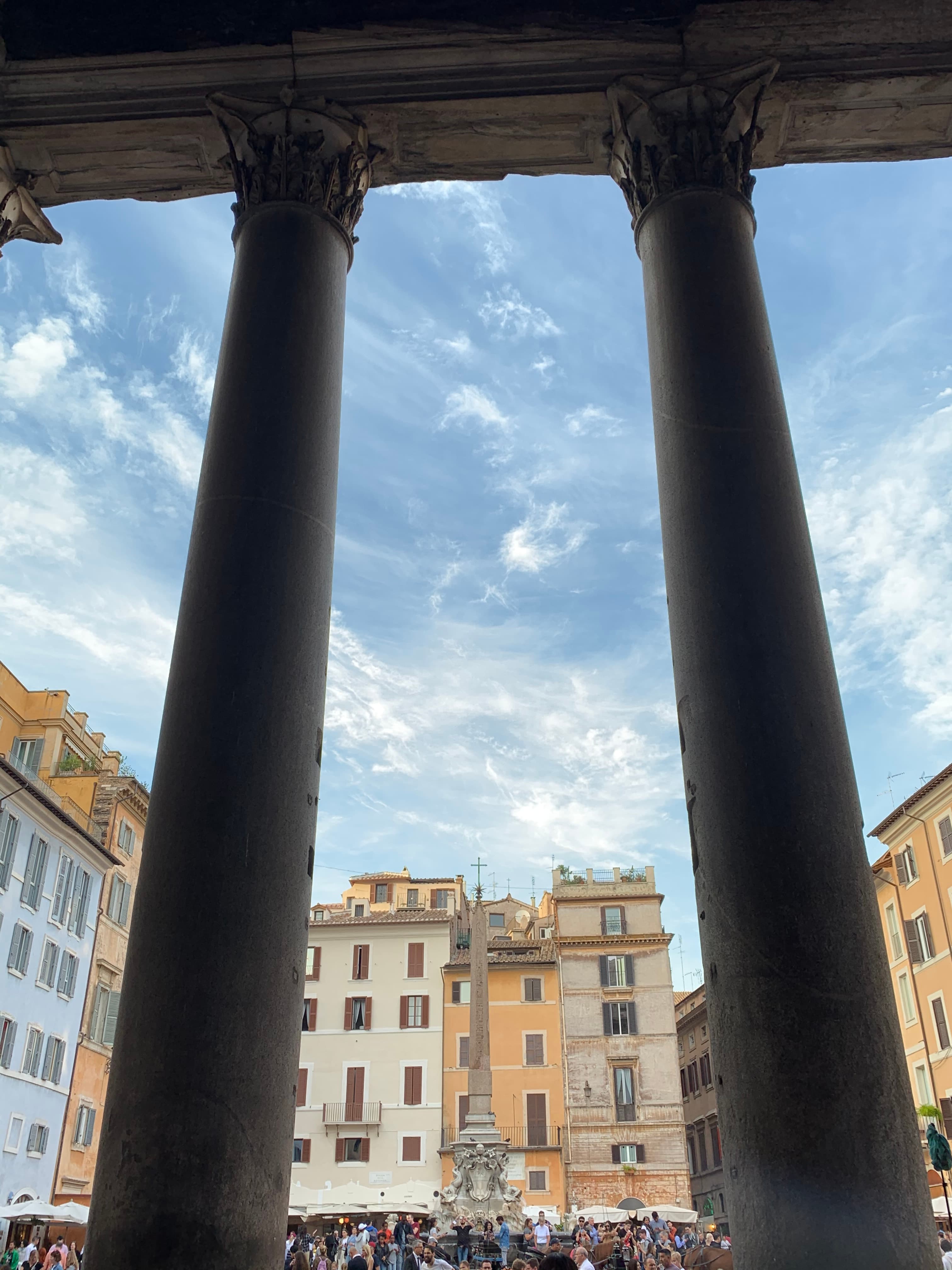 A picture of the pantheon and buildings under a blue sky with clouds