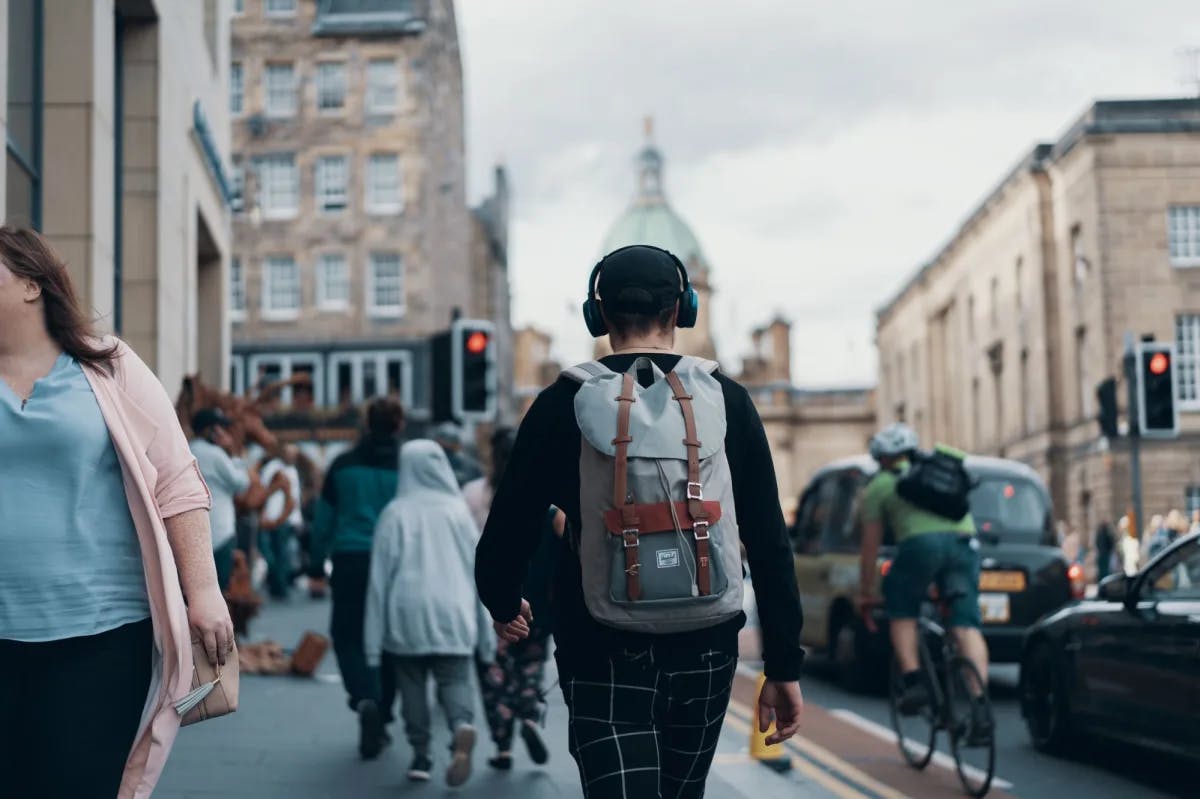 A man with a travel pack walking intently along a street in Edinburgh, Scotland