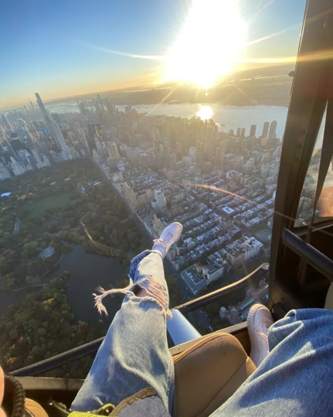 A city view from the helicopter with the skyline showing behind the view of legs and shoes seated on a chair