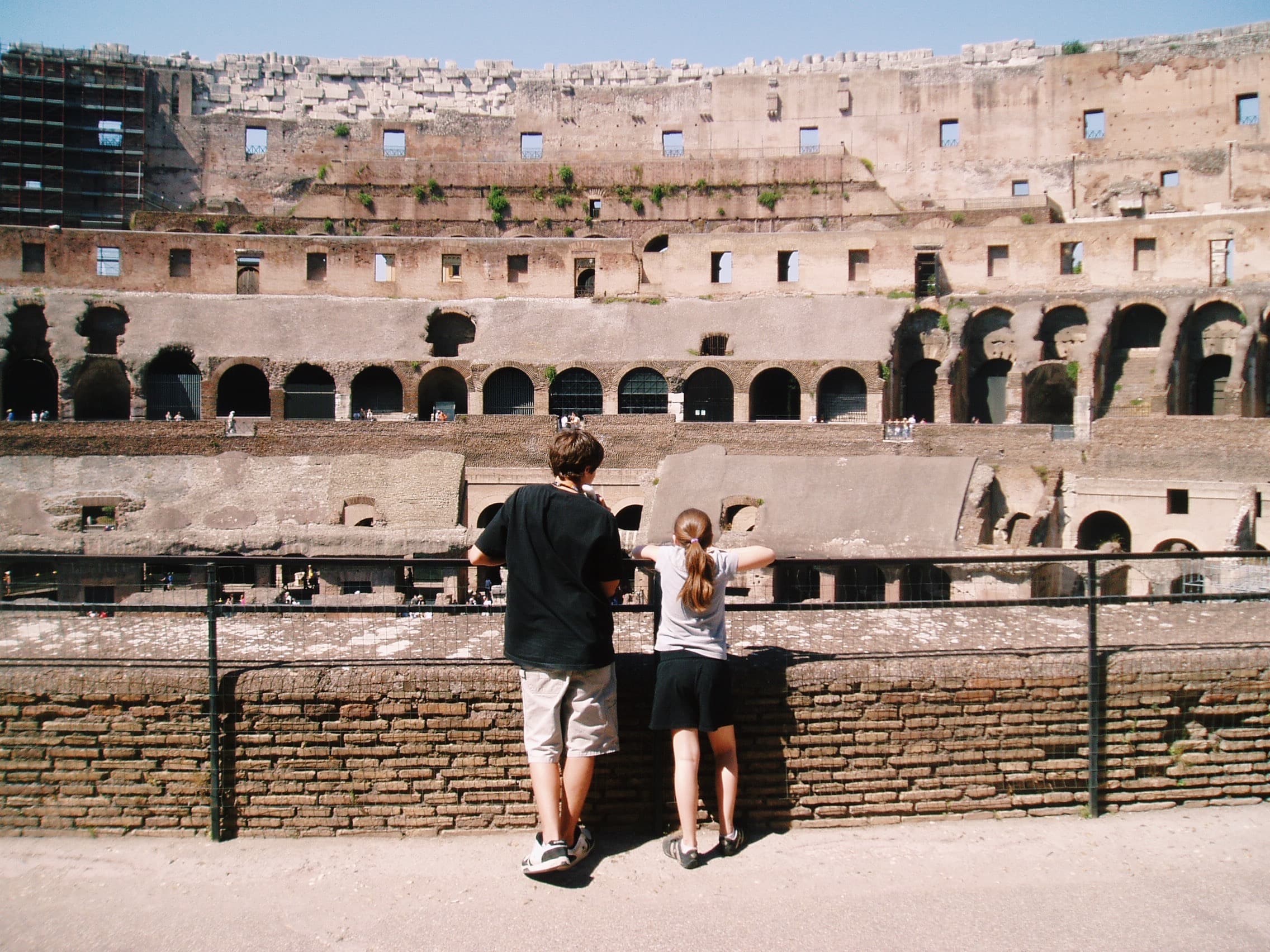 A photo of two people over looking a railing at a classic coliseum.