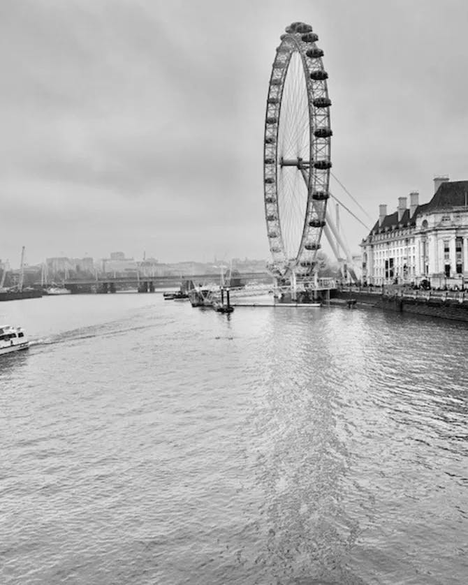 A black and white photo of the London Eye Ferris wheel over the water