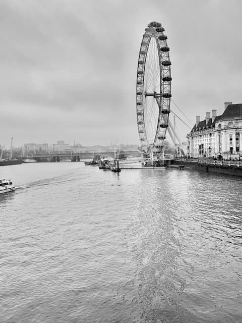 A black and white photo of the London Eye Ferris wheel over the water