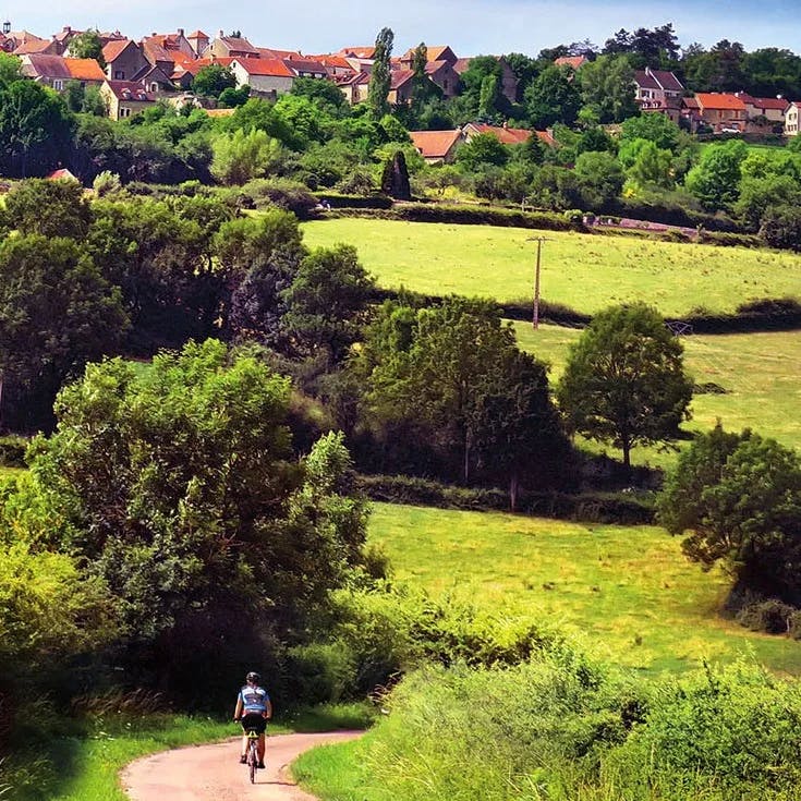 person riding a bike in a lush countryside village